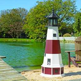 5 foot tall white and red poly lighthouse beside a pond
