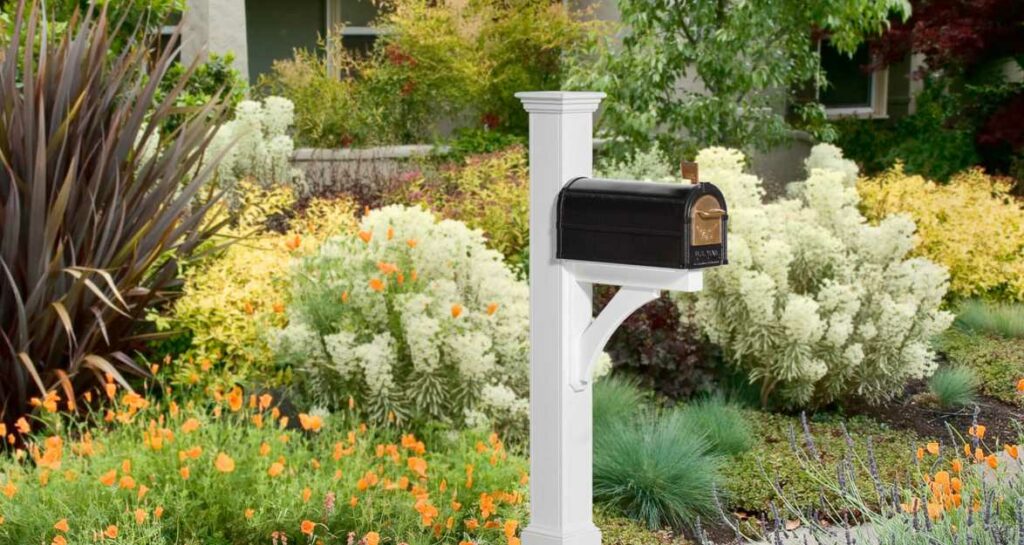 A black mailbox with a gold handle and a white post