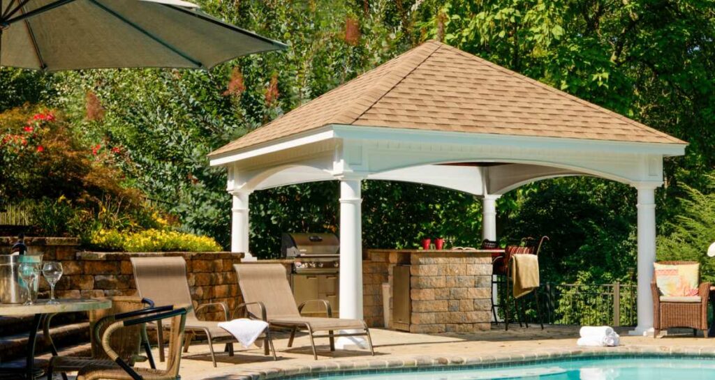 pavilion beside a pool with light brown shingles and a grill