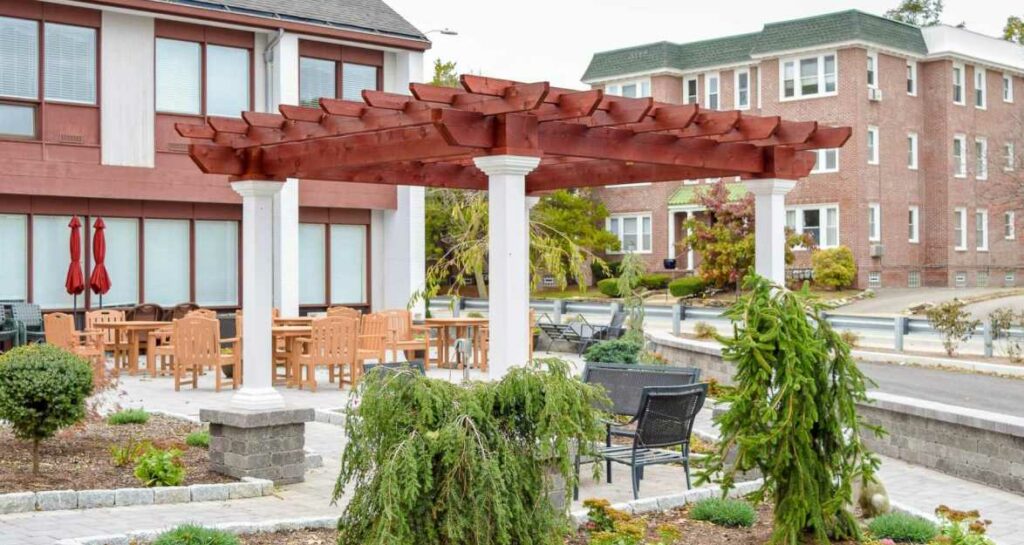 a custom pergola with white posts and a red roof