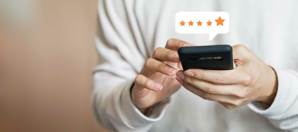 Someone holding a phone with five stars above it in a text box
