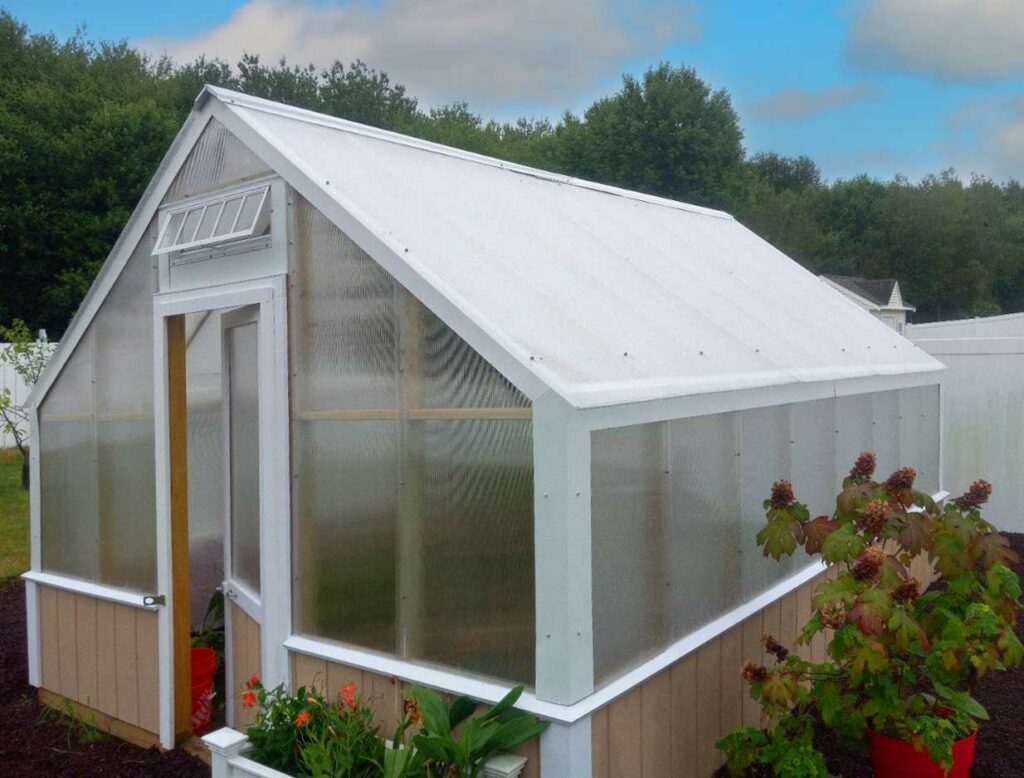 A greenhouse with a vent above the door and white trim