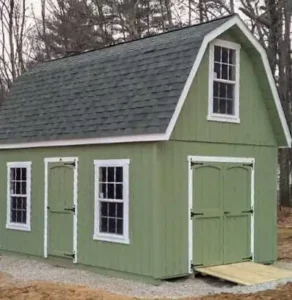 a green gambrel style garage with a dark roof