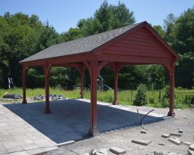 Custom pavilion featuring a gable roof design an stained wood construction with a shingle roof.