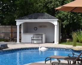 Pavilion with bar and privacy wall adds perfect addition to this backyard pool area.