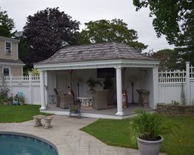 This custom pavilion features unique roof design with shake shingles and wall on the rear for privacy.