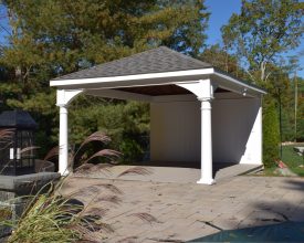 Backyard pavilion with privacy wall and electrical package, features vinyl columns and composite deck.