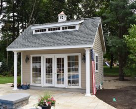 This poolhouse features full glass doors with side windows plus a dormer and cupola accent.