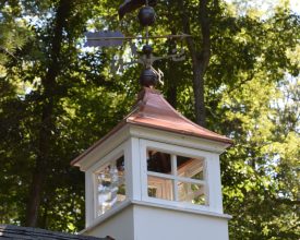 Shed cupola with copper roof and windows and weathervane.