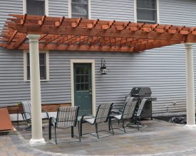 This attached to house pergola is personalized to fit the needs of the customer, with its decorative round columns and stained wood rafters.