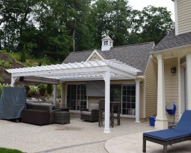 Custom attached pergola goes great in front of this poolhouse plus features a EZ shade.