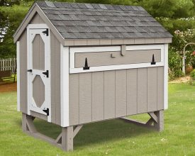 This backyard chicken coupe features, vertical painted gray siding and white trim, has large door for easy access to clean.