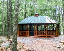 This cedar stained wood gazebo features metal roof, and screens, offers lots of room to entertain or just relax.