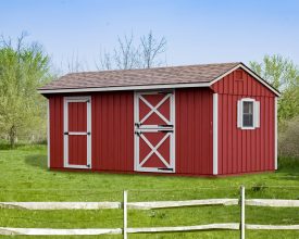 This horse barn has red painted vertical siding with shingle roof, and white trim, plus window shutters.
