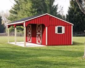 Horse barn featuring red painted vertical wood siding with white trim, and black shingle roof.
