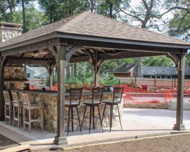 This wood pavilion is stained, and has shingled hip roof, plus bar area.