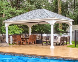 Outdoor pavilion with white vinyl wrapped columns, hip roof, and next to the pool.
