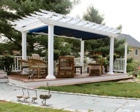 This vinyl pergola is built on a deck and features scalloped rafter tails and an ez shade.