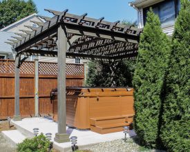 Stained wood pergola features scalloped rafter tails, and creates beautiful addition to the deck.