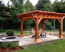 This stained wood pergola has lasting good looks, makes a enjoyable place to relax in the sun.