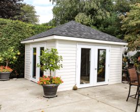 This poolhouse features square design with shingled hip room, solid panel glass doors, and vinyl siding exterior.