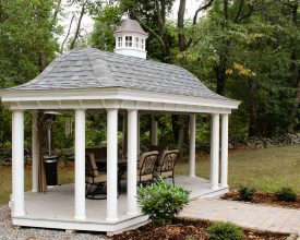 This poolhouse features unique roof design open air sitting area, with white vinyl columns.