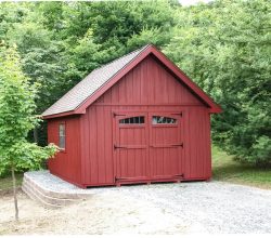 12x18 Personalized wood storage shed with painted red vertical siding, gable shingle roof, and transom windows in the doors.