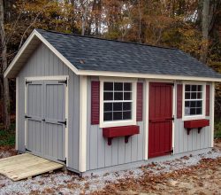 This 10x16 storage shed features vertical painted siding, window shutter and boxes, & a ramp.