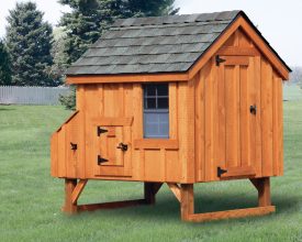 This backyard chicken coop features cedar siding, shingle roof, and is elevated from the ground.