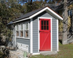 This chicken coop is custom built with extra windows, vinyl siding, and a red painted  lite door.