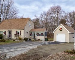This custom built single car garage includes tan vinyl siding, earthtone shingles, & concrete foundation.