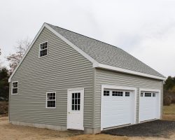 This big 2 car, 2 story garage features, gray vinyl siding, gray shingles, with concrete foundation, & personalized window placement.