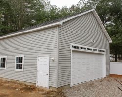 This large garage features high ceilings, very wide single garage door with transom window above, & electrical.