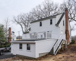 This awesome attached garage features exterior stairs, white vinyl siding, and balcony area on roof.