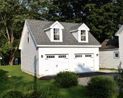 Custom 2 car garage featuring vinyl exterior siding, colonial dormers, and an upstairs loft.