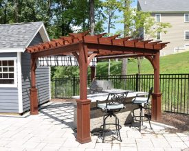Wood stained pergola with a shade canopy over an outdoor kitchen