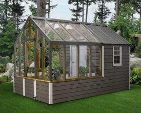A grey greenhouse with white accents and a place to keep tools