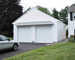 Custom 2 Car Garage featuring vinyl siding, A frame roof, and 2 bay doors.