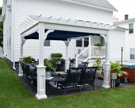 Custom vinyl pergola with superior posts and a shade canopy over an organized outdoor seating area.